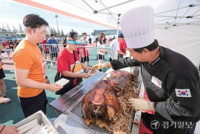 완주자들이 통돼지 바비큐를 받아들며 축제 분위기를 즐기고 있다. 조주현·윤원규기자
