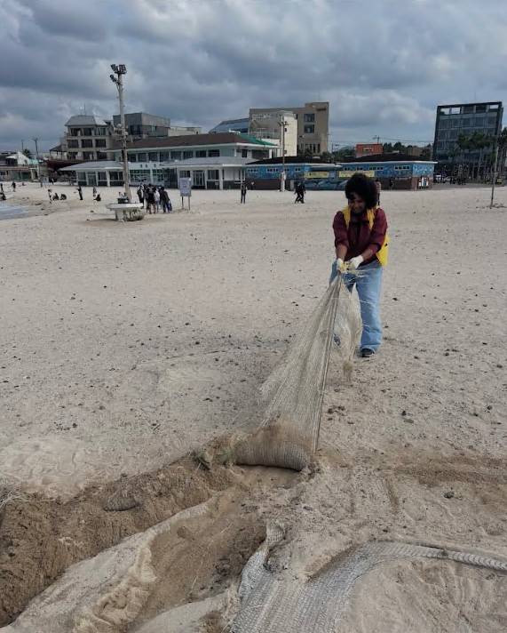 바다로 떠밀려온 대형 폐어구를 함께 끌어내고 있는 참가자들. (제주관광공사 제공)