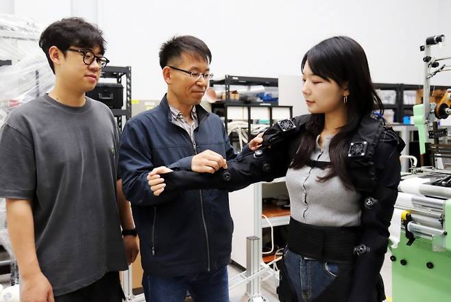 박철훈 한국기계연구원 첨단로봇연구센터 책임연구원(가운데)이 경량 의복형 웨어러블 로봇을 살펴보고 있다. 기계연 제공