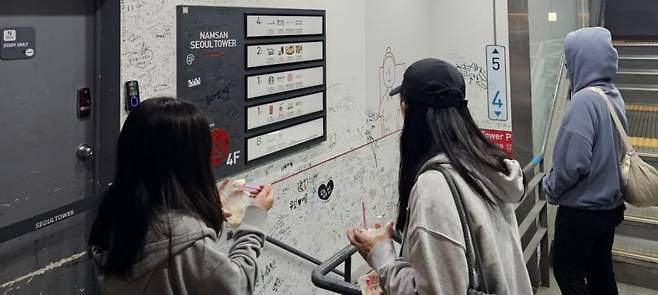 지난 8일 서울 남산타워 전망대 내부 안내판에 관광객들이 남긴 낙서가 빼곡히 적혀 있다. 한국어·영어·일본어·중국어 등 각국 언어로 이름과 날짜가 뒤섞여 있다. 사진=권용훈기자