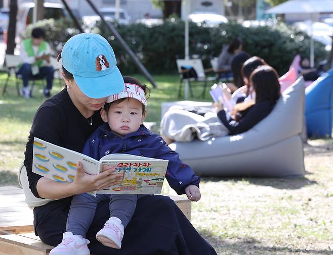 최근 서울 송파구 아시아공원을 찾은 한 가족이 동화책을 함께 읽고 있다. /연합뉴스