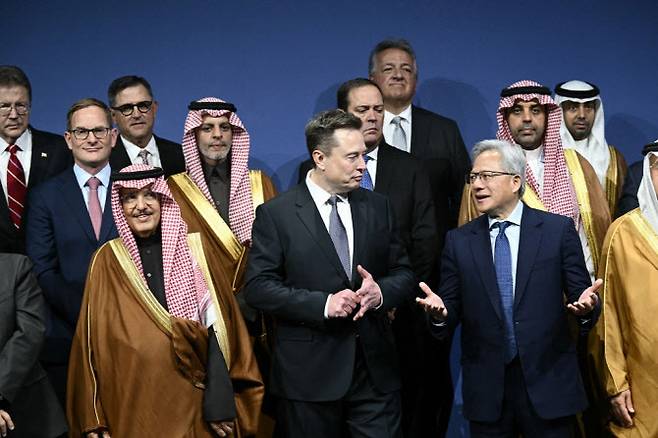 19일(현지시간) 미국 워싱턴 DC의 케네디센터에서 열린 미·사우디 투자 포럼에서 젠슨 황 엔비디아 최고경영자(CEO·오른쪽)와 일론 머스크(가운데)테슬라 CEO가 단체 사진 촬영 자리에서 논의를 하고 있다. (사진=AFP)