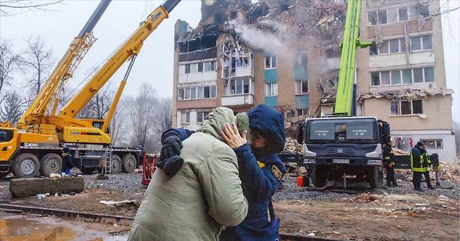 19일(현지시간) 러시아의 미사일 공격을 받은 우크라이나 테르노필의 한 아파트 앞에서 심리상담사가 주민을 위로하고 있다. /로이터연합뉴스