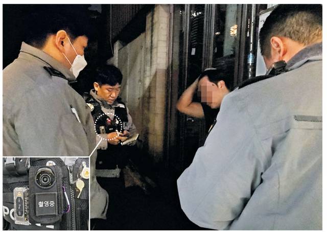 보디캠 있어 ‘든든’ : 27일 새벽 서울 마포구 홍익대 인근에 긴급 출동한 마포경찰서 홍익지구대 소속 우진수(가운데) 경사가 동료 경찰관들과 함께 폭행사건 현장을 조사하고 있다. 우 경사의 가슴 부위에 붉은 램프가 켜진 채 현장을 녹화 중인 보디캠(흰색 점선 원 안)이 보인다.