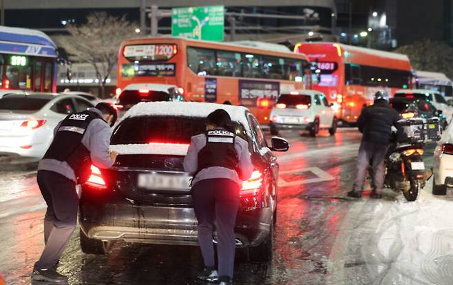 4일 서울 마포구 홍대 인근 제설작업이 완료되지 못한 도로에서 경찰들이 언덕길 차를 밀고 있다. 사진=연합뉴스
