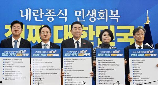 더불어민주당 김병기 원내대표 등 원내지도부가 18일 국회에서 열린 정책조정회의에서 민생 개혁 법안이 적힌 손팻말을 들고 구호를 외치고 있다. 김정록 기자