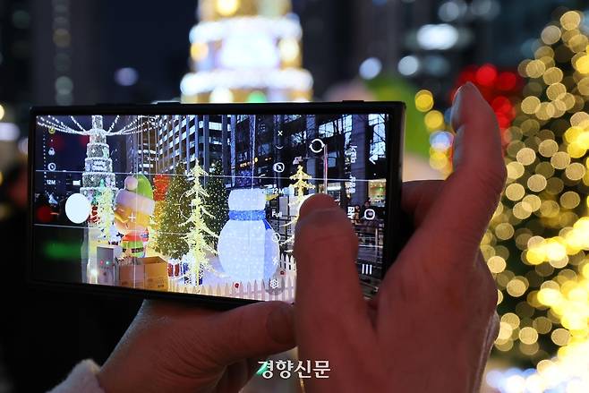 한 시민이 19일 서울 청계광장 일대에서 열리고 있는 ‘겨울, 청계천 빛’을 카메라에 담고 있다. 2025.12.19. 강윤중 기자