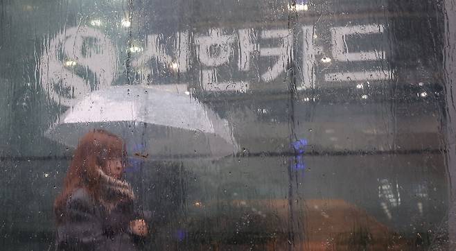 23일 오후 겨울비가 내리는 가운데 서울 중구 을지로 신한카드 본사 앞을 한 행인이 지나고 있다. 이날 신한카드는 신한카드 가맹점 대표자의 휴대전화번호를 포함해 개인정보 약 19만건이 유출된 것으로 추정돼 개인정보보호위원회에 신고했다고 밝혔다. 이승환 기자