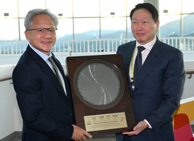 젠슨 황(왼쪽) 엔비디아 CEO가 10월31일 경북 경주시 경주예술의전당에서 열린 아시아태평양경제협력체(APEC) CEO 서밋에 참석해 최태원 SK그룹 회장 겸 대한상의 회장으로부터 SK하이닉스의 HBM4 반도체 웨이퍼를 선물로 받고 있다. 뉴스1