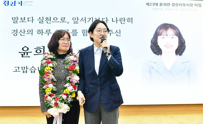 ▲ 조지연 국회의원이 이임하는 윤흐란 경산부시장에게 꽃 목걸이를 걸어준 후 응원의 말을 전하고 있다. 김윤섭기자.