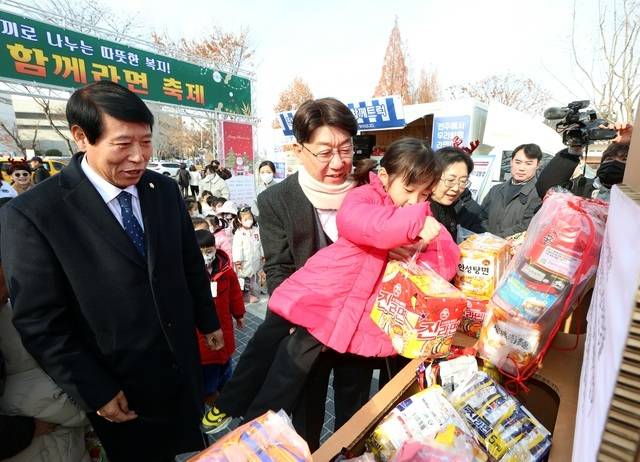 지난해 12월 10일 덕진공원에서 열린 ‘전주와 함께라면 축제’에서 우범기(왼쪽 두 번째) 전주시장이 한 아이를 안고 라면을 기부하고 있다. /전주시