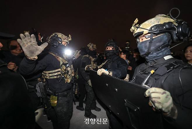 윤석열 전 대통령이 비상계엄을 선포한 후 자정을 넘긴 지난해 12월 4일 새벽 서울 여의도 국회의사당에 도착한 무장군인들이 국회 본청 진입을 시도하자 국회 직원 등이 막아서고 있다. 성동훈 기자