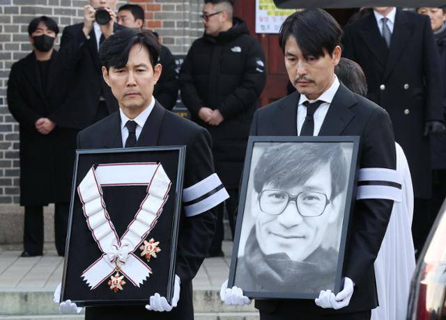 9일 서울 중구 명동성당에서 열린 배우 안성기의 장례 미사가 끝난 뒤 배우 정우성과 이정재가 고인의 영정과 금관문화훈장을 들고 있다. 연합뉴스