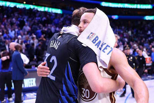 스테픈 커리가 23일 미국 텍사스주 댈러스의 아메리칸 에어라인스 센터에서 열린 댈러스 매버릭스와 2025~2026 미국프로농구 정규리그 원정 경기가 끝난 뒤 쿠퍼 플래그와 포옹하고 있다. 댈러스 | AFP연합뉴스