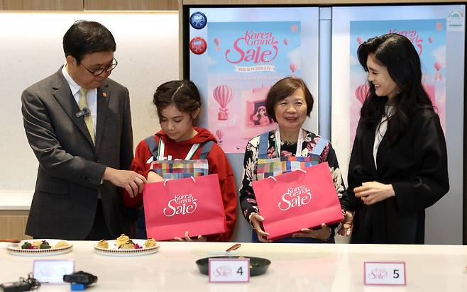 최휘영 문화체육관광부 장관이 22일 서울 영등포구 더현대 서울 문화센터에서 진행되고 있는 코리아그랜드세일의 체험행사 '케이-소스 활용 한식 쿠킹클래스'에 이부진 한국방문의해위원회 위원장과 함께 참여해 외국인 관광객에게 선물을 전달하고 있다.(사진제공=문화체육관광부)