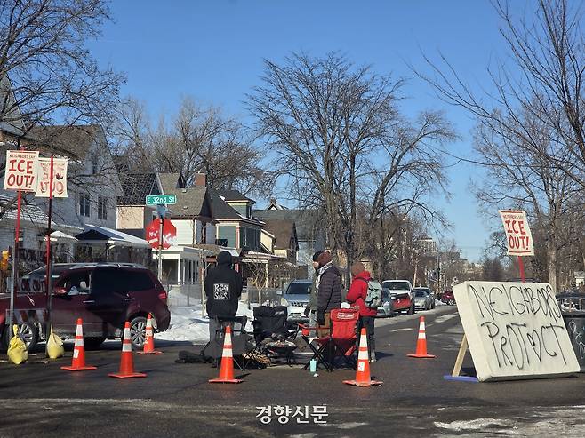 미국 미니애폴리스의 청년들이 동네 교차로에 자체 검문소를 만들어 보초를 서고 있다. 차량의 흐름을 느리게 만들어 ICE 차량이 지나가는 것을 잘 감시하기 위해서다. 이들이 써놓은 ‘이웃이 지킨다’라는 문구가 눈에 띈다. 미니애폴리스 | 정유진 특파원