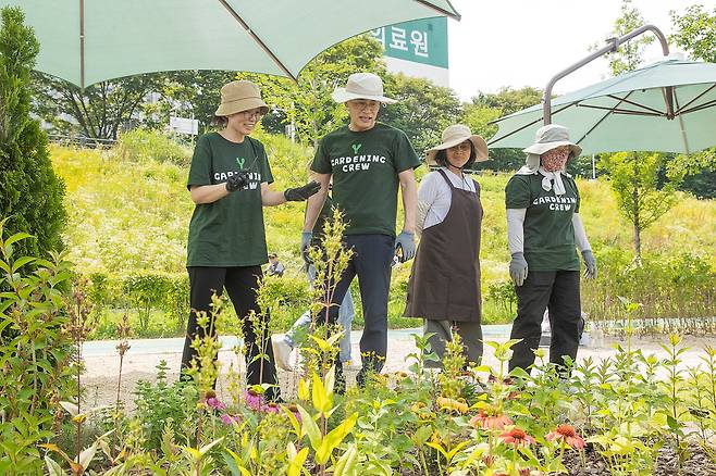이기재 양천구청장 등 녹색 티셔츠를 입고 모자를 쓴 사람들이 꽃밭에서 정원 가꾸기를 하고 있는 사진이다. 제목: “안양천에 나만의 정원을 만들어보세요”...양천구 ‘와이 가드닝크루 2기’ 모집, 내용: 안양천 유휴 녹지대 분양받아 직접 정원 조성, 관리, 기초이론부터 실습까지 제공, 2월 13일까지 ‘와이 가드닝크루 2기’ 참여자 모집... 3에서 5명 1팀 구성, 1구획 분양
