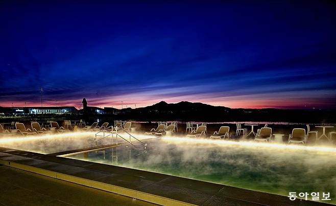 강화 석모도의 간척지 땅 너머로 펼쳐지는 새벽 일출. 유니아일랜드 더스파빌 해수온천 수영장 위로 뜨거운 수증기가 피어나고 있다.