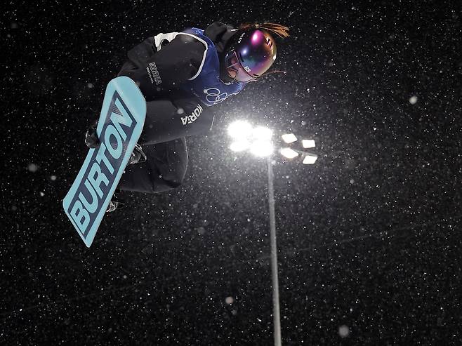 Choi Gaon soars high above the pipe while performing an aerial trick during her first run in the women’s snowboard halfpipe final at the 2026 Milan-Cortina Winter Olympics, on Thursday. (Yonhap)