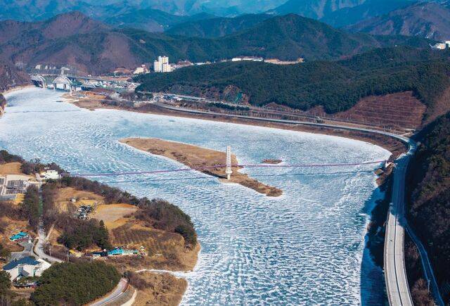 충북 단양군 '단양강'을 가로지르는 흰색 주탑의 보라색 출렁다리가 기적의 시루섬을 가로지르고 있다. 이 다리는 주변 공사를 마무리하고 다음 달 임시 개통할 예정이다. 왼쪽 앞에 수양개선사유물전시관이 보인다.