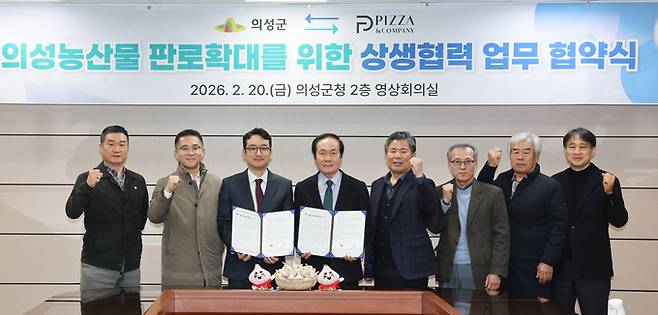 ▲ 경북 의성군 의성읍 의성군청 2층 영상회의실에서 20일 김주수 의성군수(왼쪽 네 번째)와 한동효 ㈜피자앤컴퍼니 대표(왼쪽 세 번째)가 '의성 농산물 판로확대를 위한 상생협력 업무협약'을 체결한 뒤 협약서를 펼쳐 들고 관계자들과 함께 기념 촬영을 하고 있다. 의성군 제