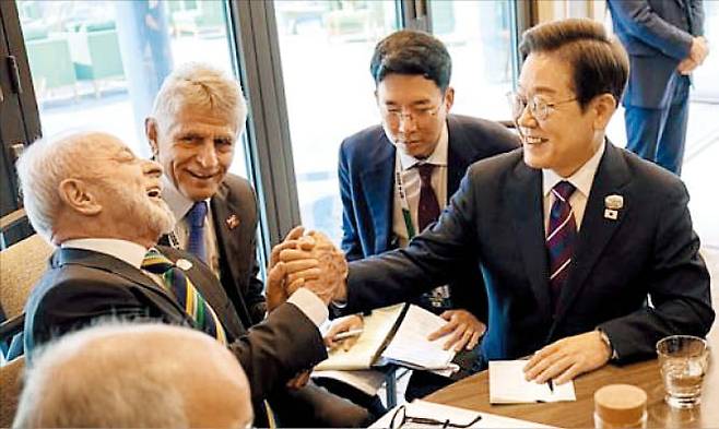 지난해 6월 캐나다에서 열린 G7 정상회의에서 처음 만난 이재명 대통령과 룰라 브라질 대통령이 회담 중 손을 잡고 웃고 있다./연합뉴스