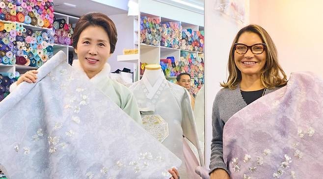 이재명 대통령의 부인 김혜경 여사(왼쪽)와 루이스 이나시우 룰라 다 시우바 브라질 대통령의 부인 호잔젤라 다 시우바 여사가 21일 서울 종로구 광장시장에서 한복 원단을 들고 포즈를 취하고 있다. 청와대 제공