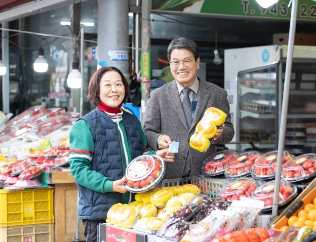 김돈곤 청양군수가 청양전통시장에서 과일을 고르며 농어촌 기본소득을 사용하는 모습