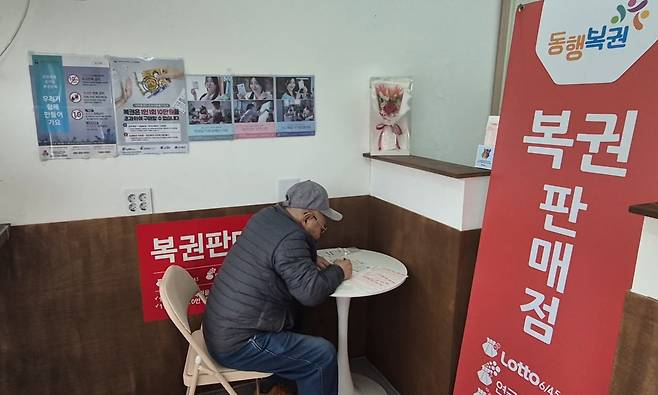 지난 23일 대학가 인근 복권방에서 노인이 직접 복권 용지에 번호를 기입하고 있다./임희재 기자