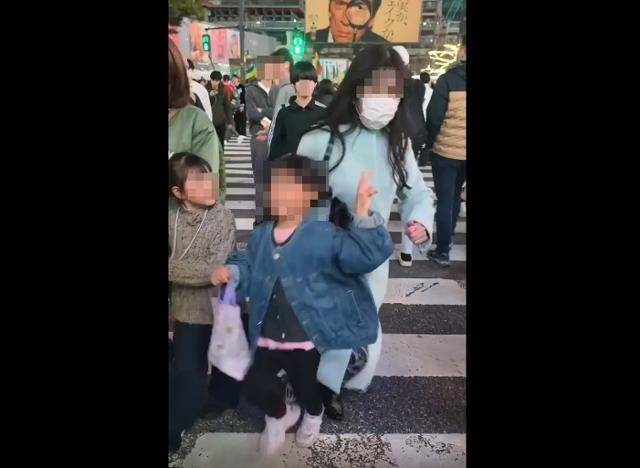 영미권 온라인 커뮤니티 사이트 '레딧(Reddit)'에 25일 올라온 영상으로, 한 성인 여성이 일본 도쿄 시부야 유명 교차로에서 포즈를 취하는 어린이를 팔꿈치로 밀치고 있다. 레딧 r/Tokyo 계정 캡처