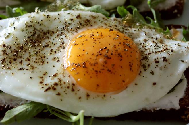 프라이팬 위에서 익어가는 달걀 위로 엑스트라버진 올리브유가 둘러지고 있다. 건강식으로 알려진 조합이지만, 올리브유 2큰술을 더하면 한 끼 열량은 380~400kcal 수준까지 올라간다. unsplash