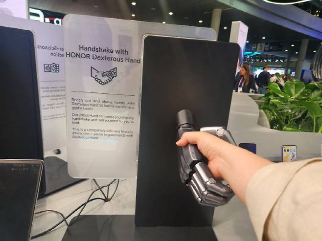 중국 스마트폰업체 아너의 MWC26 전시장에서 로봇 손과 악수를 하고 있다.(사진=이소현 기자)