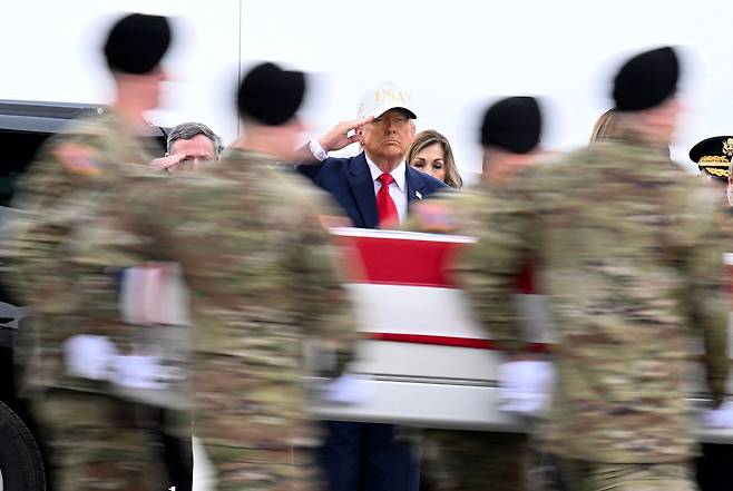 도널드 트럼프 미국 대통령(가운데)이 7일(현지시간) 미국 델라웨어주 도버 공군기지에서 열린 미군 전사자 유해 송환식에서 흰 야구 모자를 쓴 채 경례하고 있다. AFP=연합뉴스
