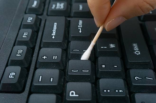 면봉으로 키보드 틈 사이를 청소하는 모습. 면봉을 이용하면 버튼 사이에 쌓인 먼지를 비교적 쉽게 제거할 수 있다. 사진=클립아트코리아