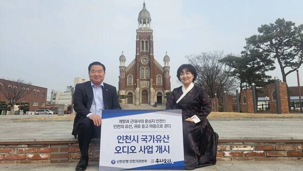 11일 남창신 신한은행 인천기관본부장(왼쪽)이 오디오 녹음에 참여한 김경아 명창과 '인천시 국가유산 오디오 가이드' 첫번째 설치 장소인 답동성당 앞에서 환하게 웃고 있다. <신한은행 제공>