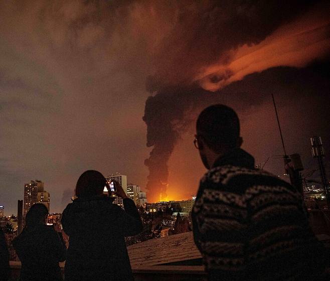 7일(현지시각) 이란 테헤란에서 석유 저장고가 공격받아 화염이 치솟는 모습을 테헤란 주민들이 촬영하고 있다. ISNA AP 연합뉴스