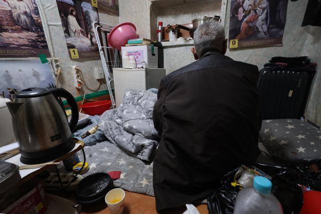 서울 최저기온이 영하 12도까지 떨어지며 한파가 절정에 달한 1월 서울 용산구 동자동 쪽방촌에서 한 주민이 외투를 입은 채 이불을 덮고 있다. 연합뉴스