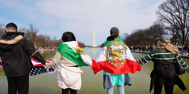 전쟁 끝나길 바라는 마음으로…손에 손잡고 링컨 기념관 빙 두른 시민들 이란 공격을 반대하는 미국 시위대가 14일(현지시간) 워싱턴의 링컨 기념관 앞에 있는 ‘반사의 연못’을 둘러싸고 ‘이란을 위한 인간 사슬’ 집회를 하고 있다. AFP연합뉴스