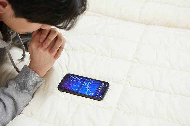 심야 시간, 해외 증시 개장과 함께 다시 켜지는 스마트폰 화면. 가계 자산이 금융 중심으로 재편되면서 투자는 이제 재테크를 넘어 ‘내일의 안전’을 확보하려는 필사적인 전략이 됐다. 게티이미지