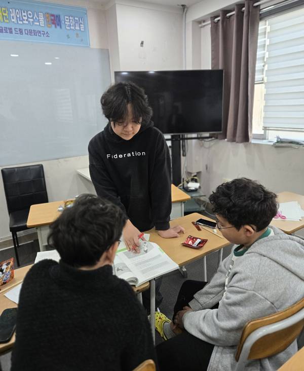 드미트리가 후배들에게 한국어 쓰기를 가르치고 있다.