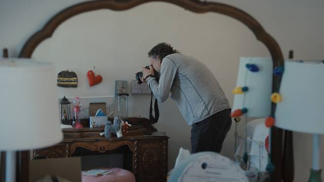 넷플릭스 다큐멘터리 <텅 빈 모든 방> 한 장면. 사진 작가 루 보프가 학교 총격 사건으로 숨진 한 아이의 방을 촬영하고 있다. 넷플릭스 제공