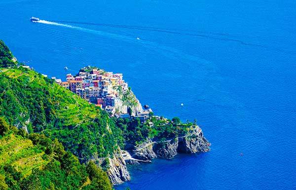 절벽 위에 형형색색의 집들이 모여 있는 친퀘테레 마을 전경. 바다와 산이 맞닿은 해안 풍경이 인상적이다.