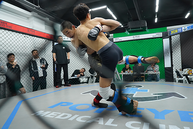 플라이급 챔피언 문순수가 2026년 3월 KMMA 타이틀 방어전에서 도전자로 나선 밴텀급 챔피언 변상민의 발목을 걸어 넘어뜨리려 하고 있다. 사진=뽀빠이연합의원KMMA파이터에이전시 제공