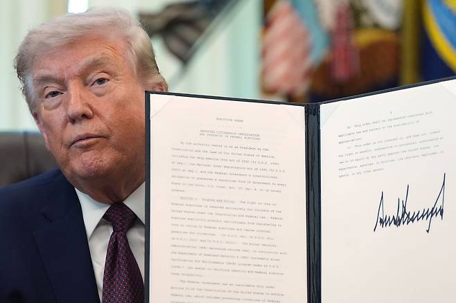지난달 31일(현지시간) 도널드 트럼프 미국 대통령이 백악관에서 서명한 행정명령서를 기자들에게 공개하고 있다. AP=연합뉴스