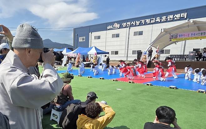 ▲ 홍서 스님이 제16회 영천복사꽃 전국사진촬영대회에서 경상북도체육회 독도사랑스포츠공연단 시범공연을 촬영하고 있다. 권오석 기자