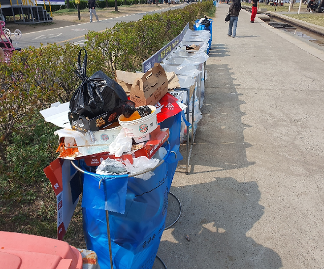 지난 3일 여의도 한강공원 산책로에 설치된 쓰레기통이 음식 용기와 포장재로 넘쳐나고 있다. 벚꽃축제 개막과 함께 방문객과 노점 이용이 늘면서 분리수거가 제대로 이뤄지지 않은 채 쓰레기가 방치된 모습. 사진=최승한 기자