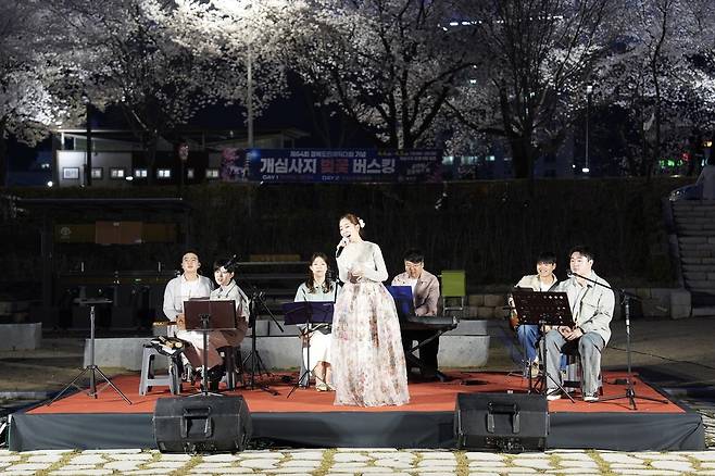만개한 벚꽃이 조명을 받으며 밝게 빛나는 야경 속에서 전통 국악기와 밴드 사운드를 결합한 독창적인 무대를 선보이고 있는 모습. /예천군 제공