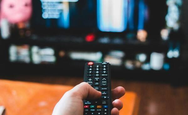 ▲화면에 콘텐츠가 띄워져 있는 TV를 향해 리모컨을 들고 있는 손이 보이는 이미지. 사진=unsplash