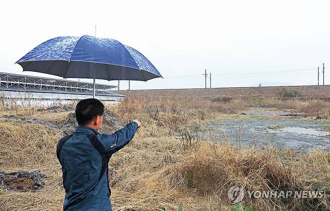 폐기물이 매립된 밀양 농지 일대 (창원=연합뉴스) 이준영 기자 = 9일 오전 경남 밀양시 삼랑진읍 한 농지에 폐기물이 매립된 곳을 인근 축사 업주가 가르키고 있다. 2026.4.9 ljy@yna.co.kr