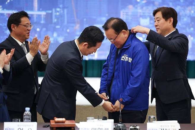 더불어민주당 정청래 대표가 8일 대구 북구 인터불고 엑스코 호텔에서 열린 더불어민주당 현장 최고위원회의에서 대구시장 후보인 김부겸 전 국무총리에게 당 점퍼를 입혀주고 있다. 연합뉴스